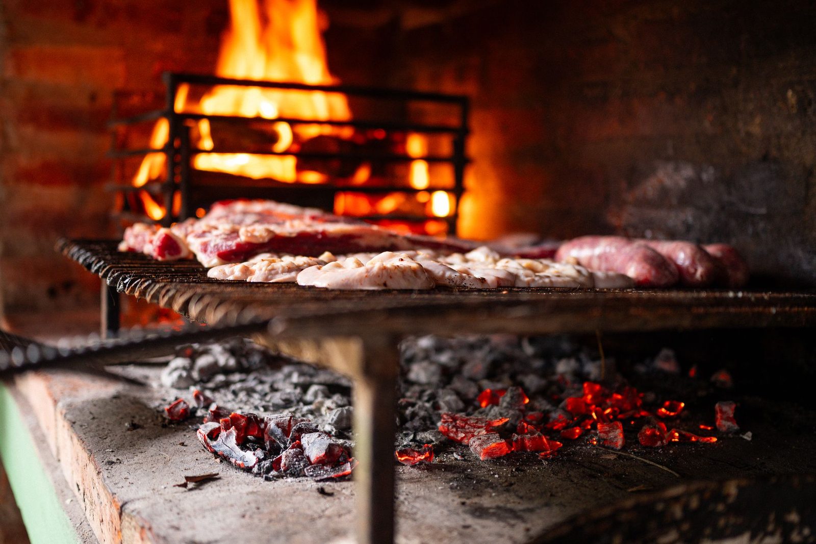 Meat cooking over glowing coals at a Spitbraai Masters function