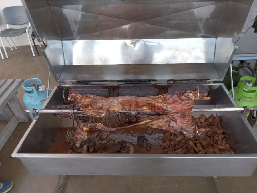 A whole lamb spit braai turning over the coals at a garden function